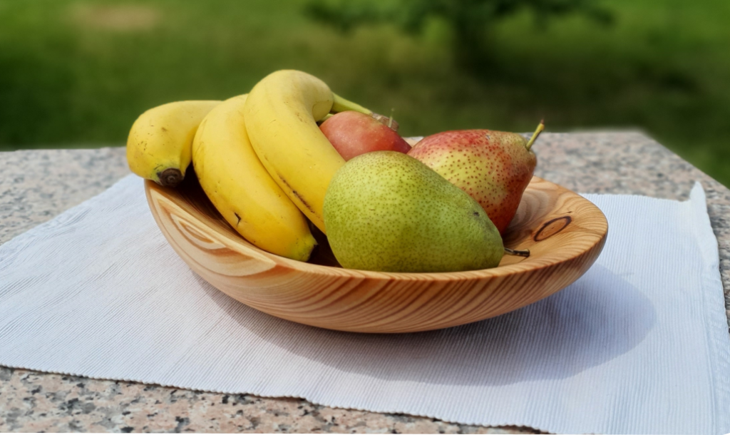 Handgefertigte Schale aus Lärchenholz mit Obst auf einem Tisch